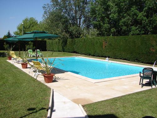 a swimming pool in a yard with a umbrella at The Originals City, Hôtel Le Sextant, Toulouse Sud in Labège