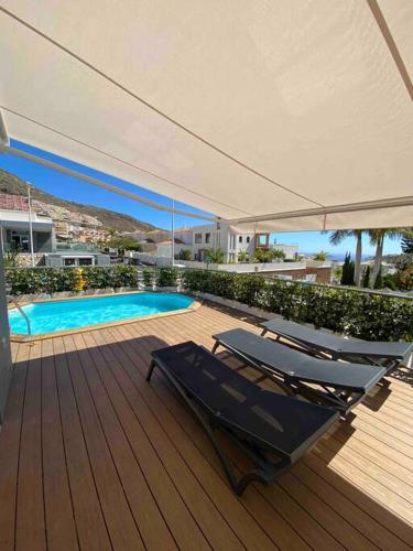 una terraza con sillas, una sombrilla y una piscina en Sunset of Duke#Luxury Costa Adeje, en Adeje