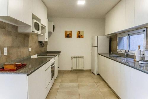 a kitchen with white cabinets and a white refrigerator at Moderno Dpto en zona de bodegas in Ciudad Lujan de Cuyo