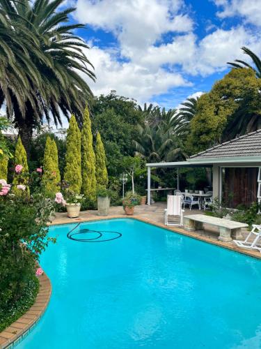 une grande piscine bleue avec une terrasse et des arbres dans l'établissement Somerset West Garden Apartments 1, à Somerset West