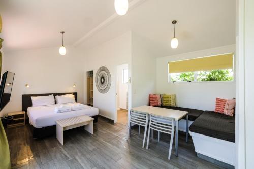 ワイヒ・ビーチにあるTasman Holiday Parks - Waihi Beachのベッド2台、テーブル、ソファが備わる客室です。