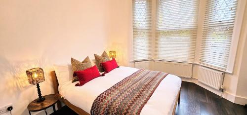 una camera da letto con un grande letto bianco con cuscini rossi di Victorian Property a Londra