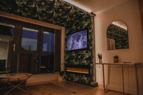 een woonkamer met een open haard en een tv aan de muur bij The Opulence in Bradford