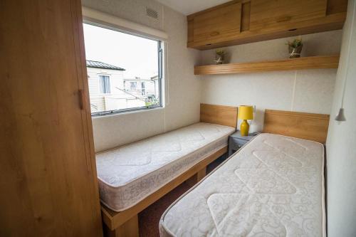 a small room with two beds and a window at Great 4 Berth Caravan At Withernsea Sands Ref 79003hg 