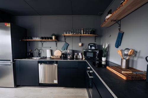 a kitchen with black cabinets and a stainless steel refrigerator at Golden Circle Luxury Cottages Lake View in Selfoss