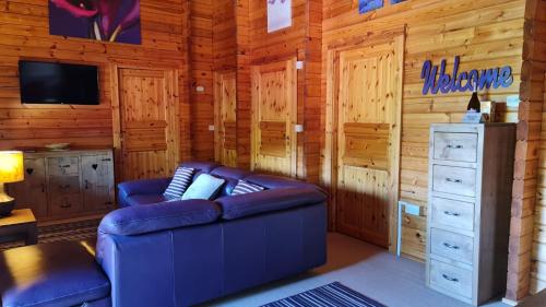 a living room with a couch and a tv and wooden walls at 3-Bed Lodge - Sleeps 7 - Hot Tub - Pet Friendly in Skipton