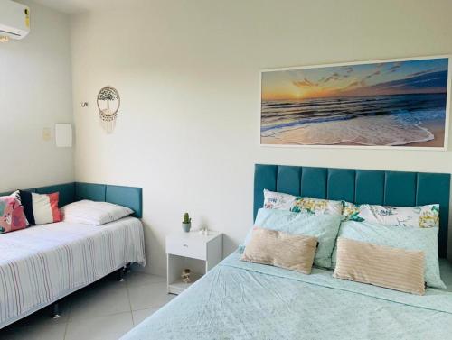 Apto Vista Mar - Jacumã في كوندي: غرفة نوم بسريرين ولوحة على الحائط