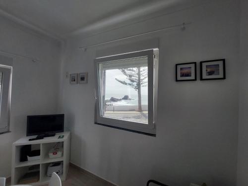 a living room with a window and a television at a casinha da avó in Zambujeira do Mar