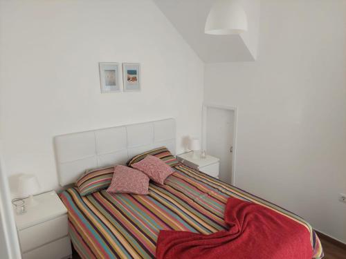 um quarto com uma cama com duas almofadas cor-de-rosa em a casinha da avó na Zambujeira do Mar