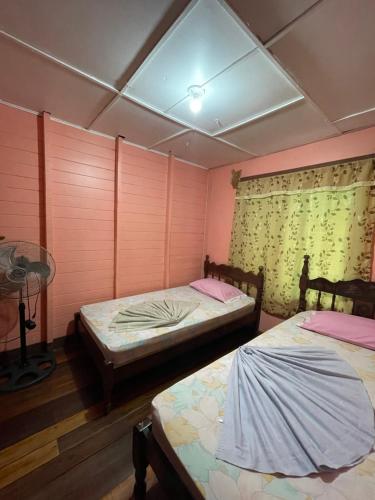 two beds in a room with pink walls at Pura Vida Hostel in Montezuma