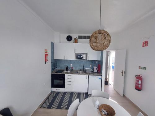 a kitchen with white cabinets and a table in it at a casinha da avó in Zambujeira do Mar