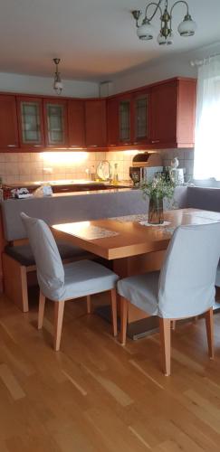 cocina con mesa de madera y 2 sillas blancas en Mountain peaks Apartment with Sauna en Gozd Martuljek