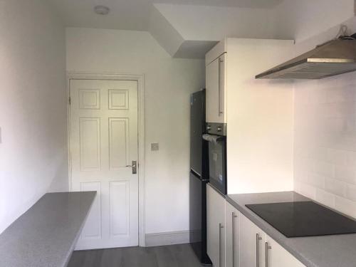 uma cozinha com paredes brancas e uma porta branca em 3 BEDROOM HOUSE IN A GREAT LOCATION em Childwall
