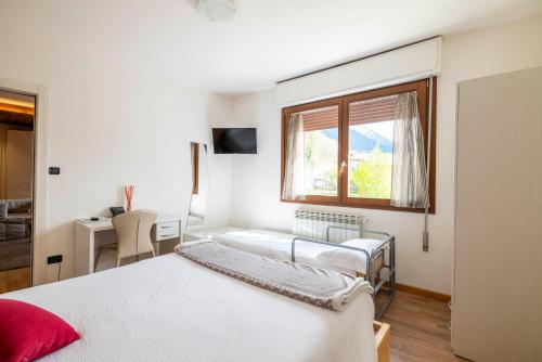 1 dormitorio con 2 camas, escritorio y ventana en B&B Castello Cimbergo, en Cimbergo