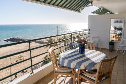 a balcony with a table and chairs and the beach at Ocean Blue II in Quarteira