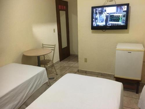 a room with a bed and a tv on the wall at HOTEL CENTER Ribeirão in Ribeirão Preto