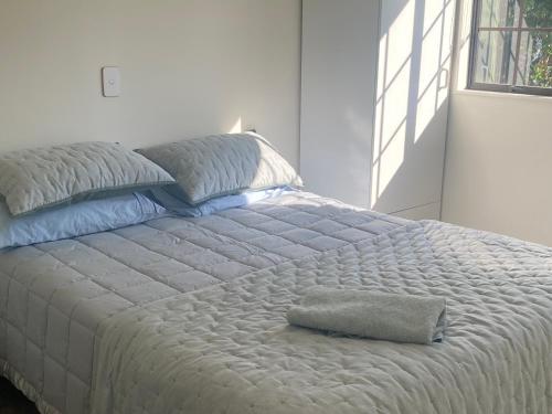 a white bed with a pillow on top of it at Bright Cosy Cottage in Whitianga