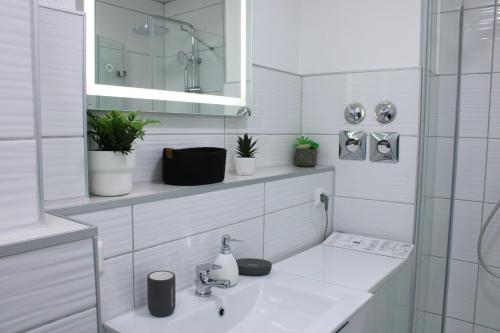 La salle de bains blanche est pourvue d'un lavabo et d'un miroir. dans l'établissement Zentrales schickes Apartment, à Heilbronn
