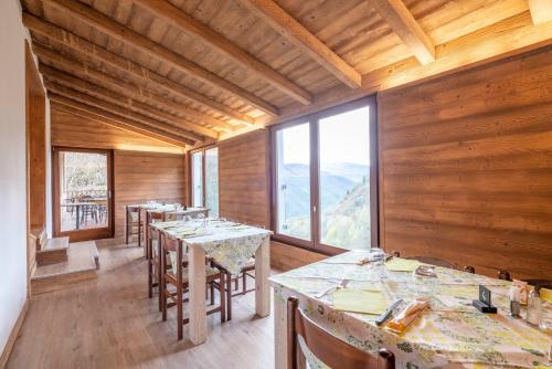 Zimmer mit Holzwänden, Tischen und Fenstern in der Unterkunft B&B Castello Cimbergo in Cimbergo