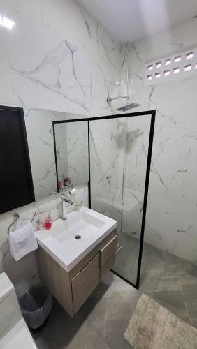 a bathroom with a sink and a glass shower at Amazonia Deluxe Calle 13 in Leticia