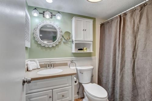 a bathroom with a toilet and a sink and a mirror at Sol Y Mar A103 Surf Racquet Club in Fernandina Beach
