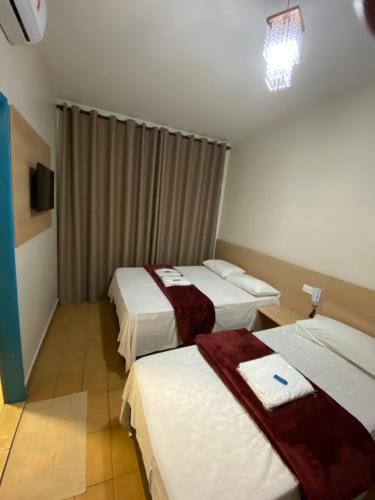 Habitación de hotel con 3 camas y lámpara de araña. en Hotel Novo México en Guarulhos