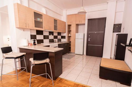 a kitchen with a counter and chairs and a refrigerator at Lilly's House in Volos