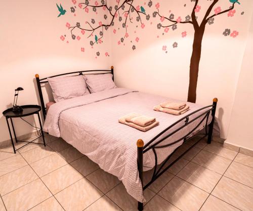 a bedroom with a bed with a tree on the wall at Lilly's House in Volos