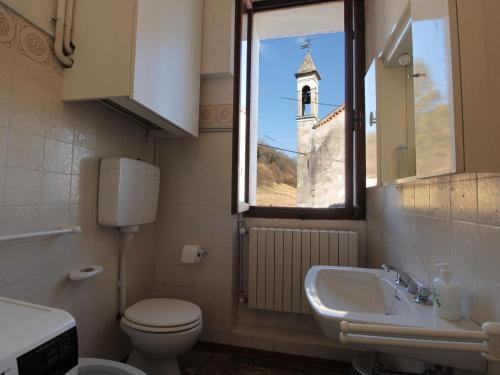 a bathroom with a toilet and a sink and a window at Spacious apartment in Santa Giustina with shared swimming pool in Santa Giustina