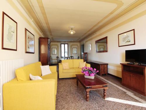 a living room with yellow furniture and a tv at Apartment in Valbelluna with Pool & Dolomites View in Santa Giustina