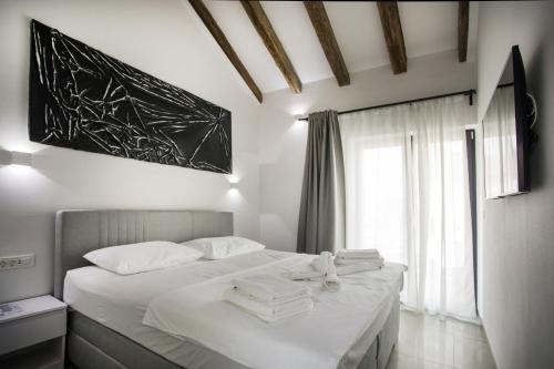 Schlafzimmer mit einem Bett mit weißer Bettwäsche und einem Fenster in der Unterkunft Luxury villa with a swimming pool Privlaka, Zadar - 18623 in Privlaka