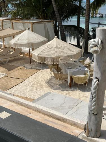 een groep tafels en stoelen met parasols op het strand bij Maria's Kan Kin in Isla Mujeres