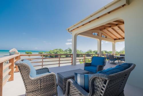 a patio with wicker chairs and a table on a deck at Suite 2 at Island Pearl Gold Standard Certified in Caye Caulker