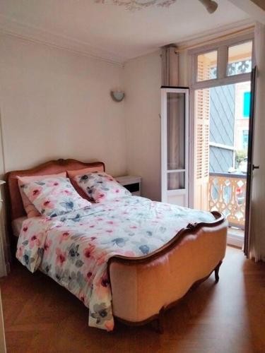une chambre avec un lit avec une couette fleurie dans l'établissement Appartement avec balcon / jardin, à Mers-les-Bains