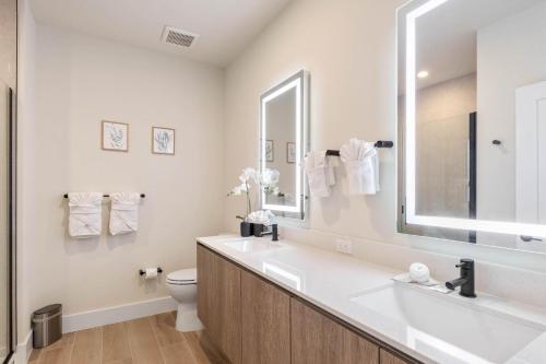 La salle de bains est pourvue d'un lavabo, de toilettes et d'un miroir. dans l'établissement 4 bedrooms pool home Hidden Forest Resort Amenities, à Orlando