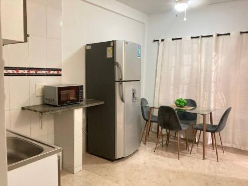 a kitchen with a black refrigerator and a table with chairs at Apartamento el Calamar in Cartagena de Indias