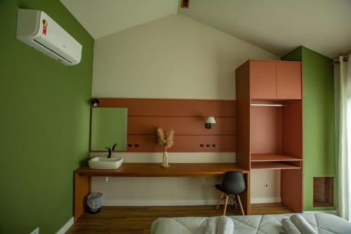 1 dormitorio con paredes verdes y blancas y escritorio en Chakras Pousada, en Jaguariaíva