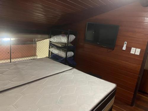 een kleine kamer met een bed en een televisie bij Winterville 618 Flat Gravatá in Gravatá