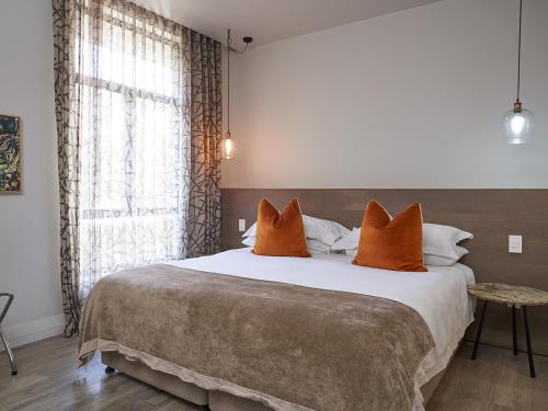 ein Schlafzimmer mit einem großen Bett mit orangefarbenen Kissen in der Unterkunft aha The Rex Hotel in Knysna