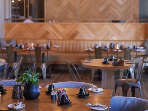 a dining room with wooden tables and chairs and a table with a plant at aha The Rex Hotel in Knysna