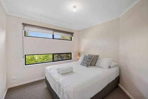 a white bedroom with a large bed and two windows at Blue Lagoon Coastal Retreat - Falmouth in Falmouth