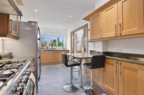 a kitchen with wooden cabinets and a table and chairs at The Roost Group - 8-Bed Home - Hot Tub WiFi Parking in Gravesend