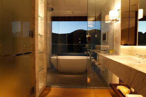 a bathroom with a tub and a sink and a shower at OliveBay Hotel in Saikai