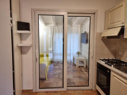 une cuisine avec une porte coulissante en verre menant à une chambre. dans l'établissement Lulamax Sardegna Olbia, à Olbia