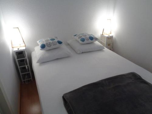 une chambre avec un grand lit blanc avec deux lampes dans l'établissement Charmant T2 avec Terrasse Sud, Accès Plage et Parking Sécurisé à Arcachon - FR-1-374-85, à Arcachon