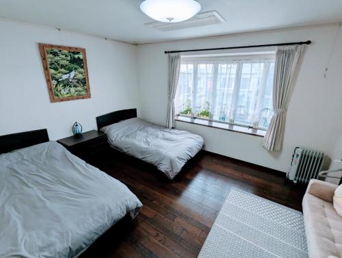sypialnia z 2 łóżkami i oknem w obiekcie 柳川ゲストハウス 憩 (IKOI) w mieście Yanagawa