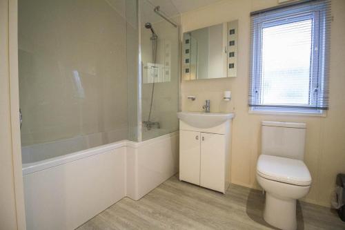 y baño con aseo, lavabo y ducha. en Luxury Platinum Lodge At Suffolk Sands Holiday Park Ref 45009mv en Felixstowe