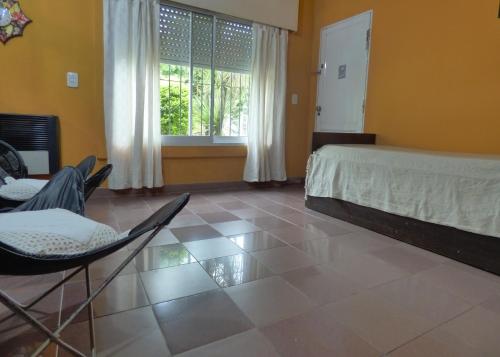 a bedroom with a bed and chairs and a window at Alojamiento Passiflora I in Villa Elisa