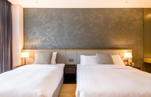 two beds in a hotel room with white sheets at The Grand Sumorum in Seogwipo