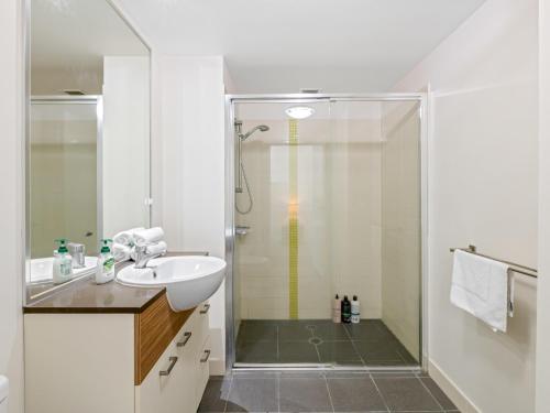 een witte badkamer met een douche en een wastafel bij City Centre 3BR Apartment with Stunning Views in Brisbane